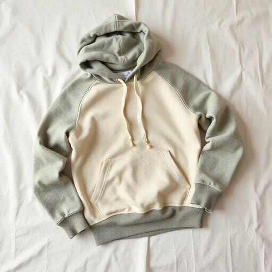 Folded hoodie on light fabric with natural-texture material swatches in muted colors